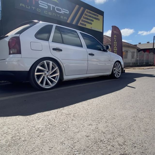 Carro branco rebaixado em frente à oficina